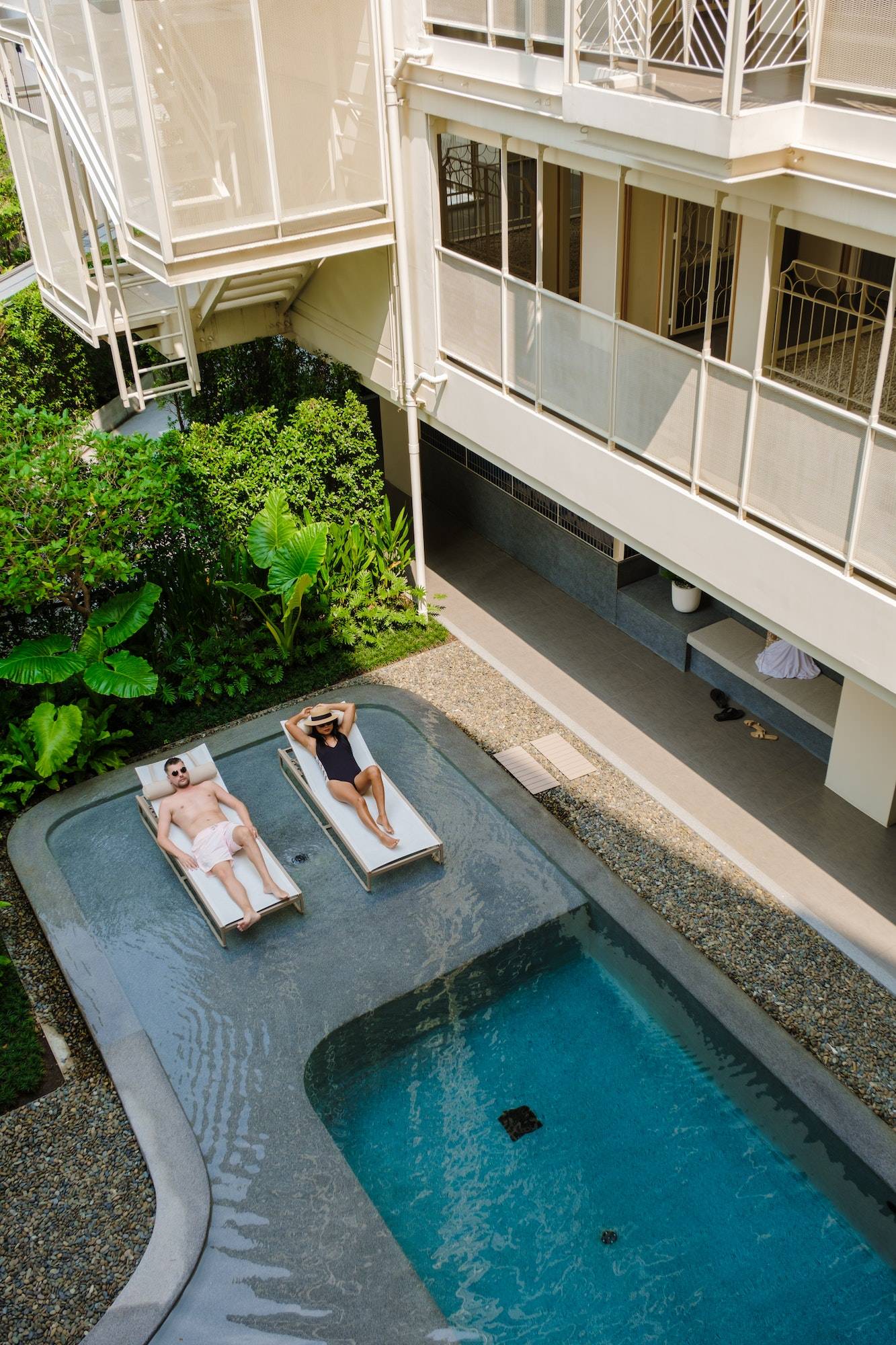 couple at a swimming pool at an art deco luxury hotel architecture from the 80s